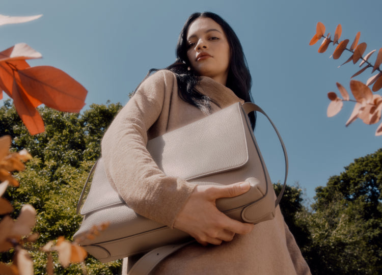 Person carrying a large handbag outdoors.