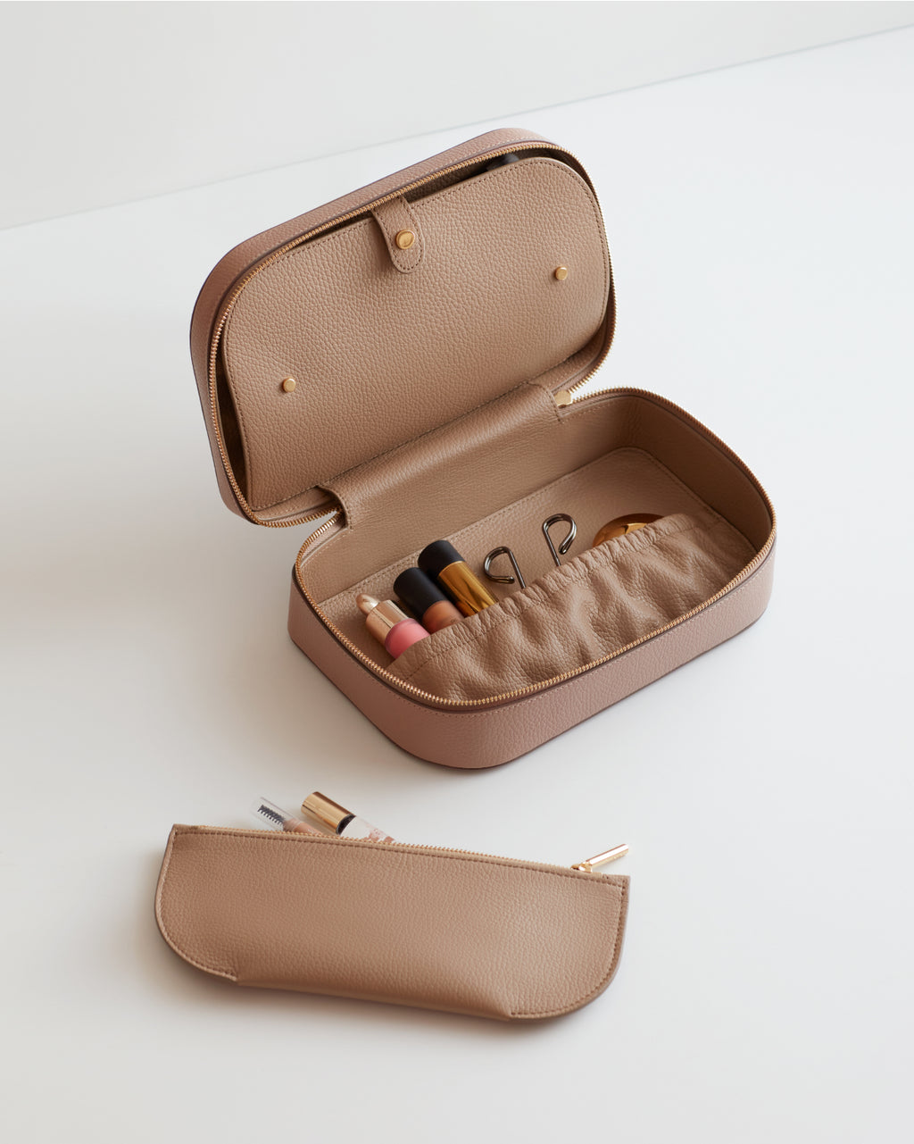 Open cosmetics case with makeup items inside and a pouch beside it.