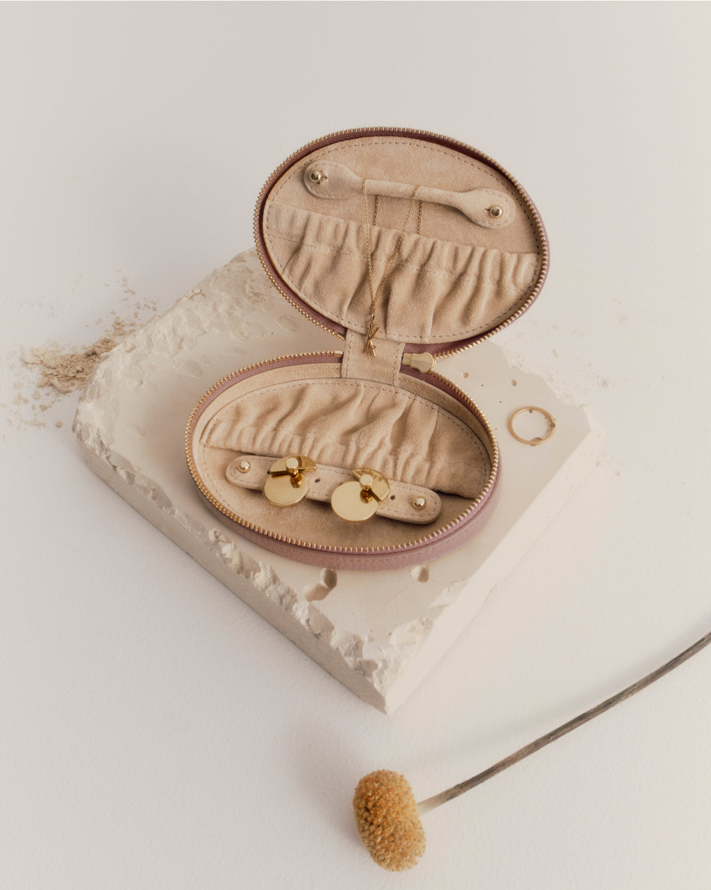 Open jewelry pouch with items on a book, next to a brush.