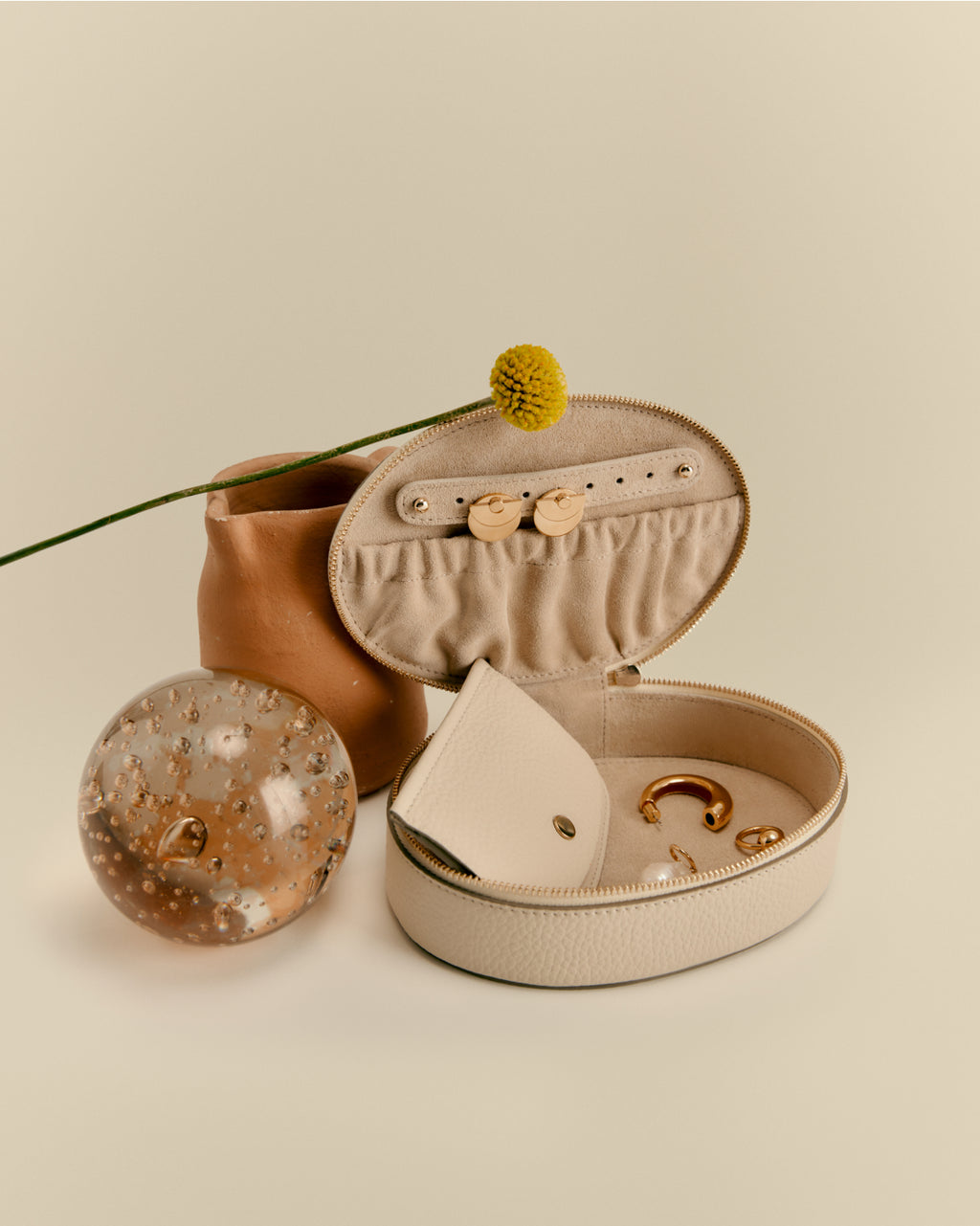 Jewelry box open with jewelry inside, next to a vase and decorative sphere.