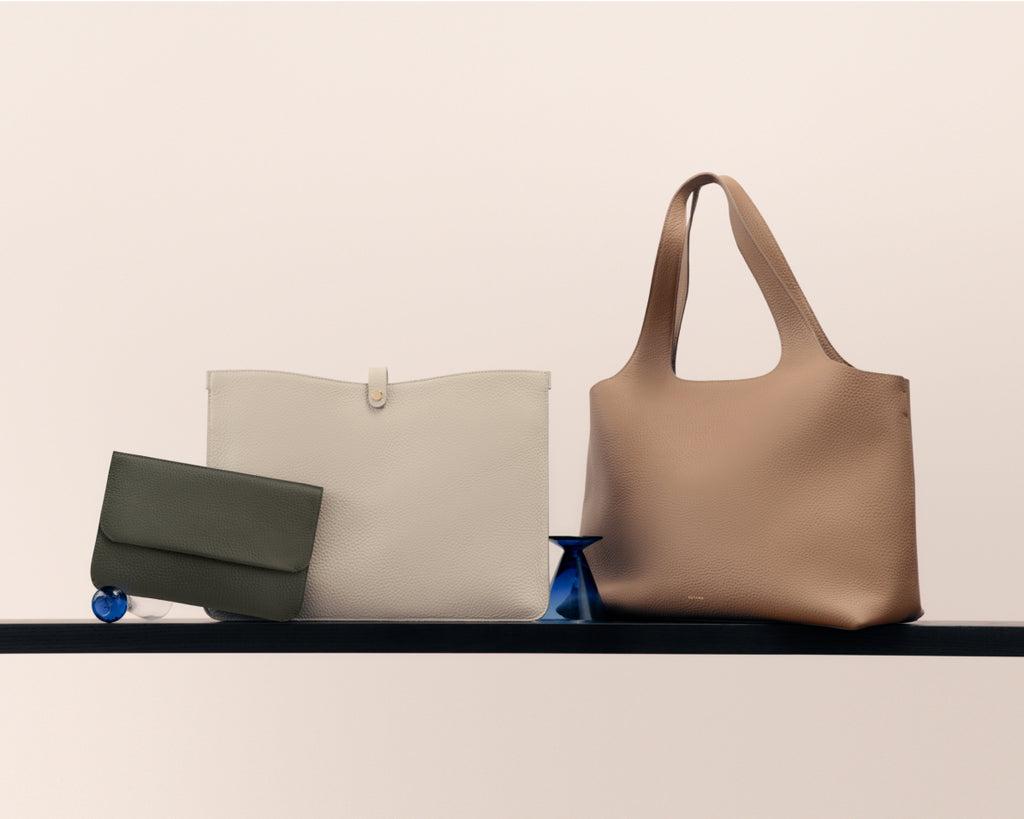 Three bags on a shelf, including one clutch and two larger bags.