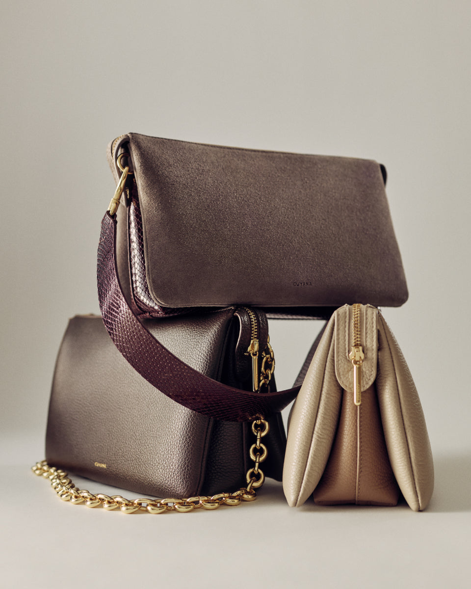 Three handbags with shoulder straps and chain accents displayed together.