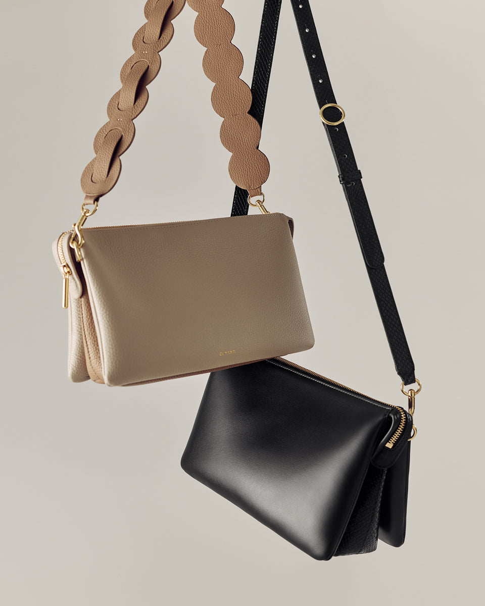 Two handbags hanging with decorative straps.
