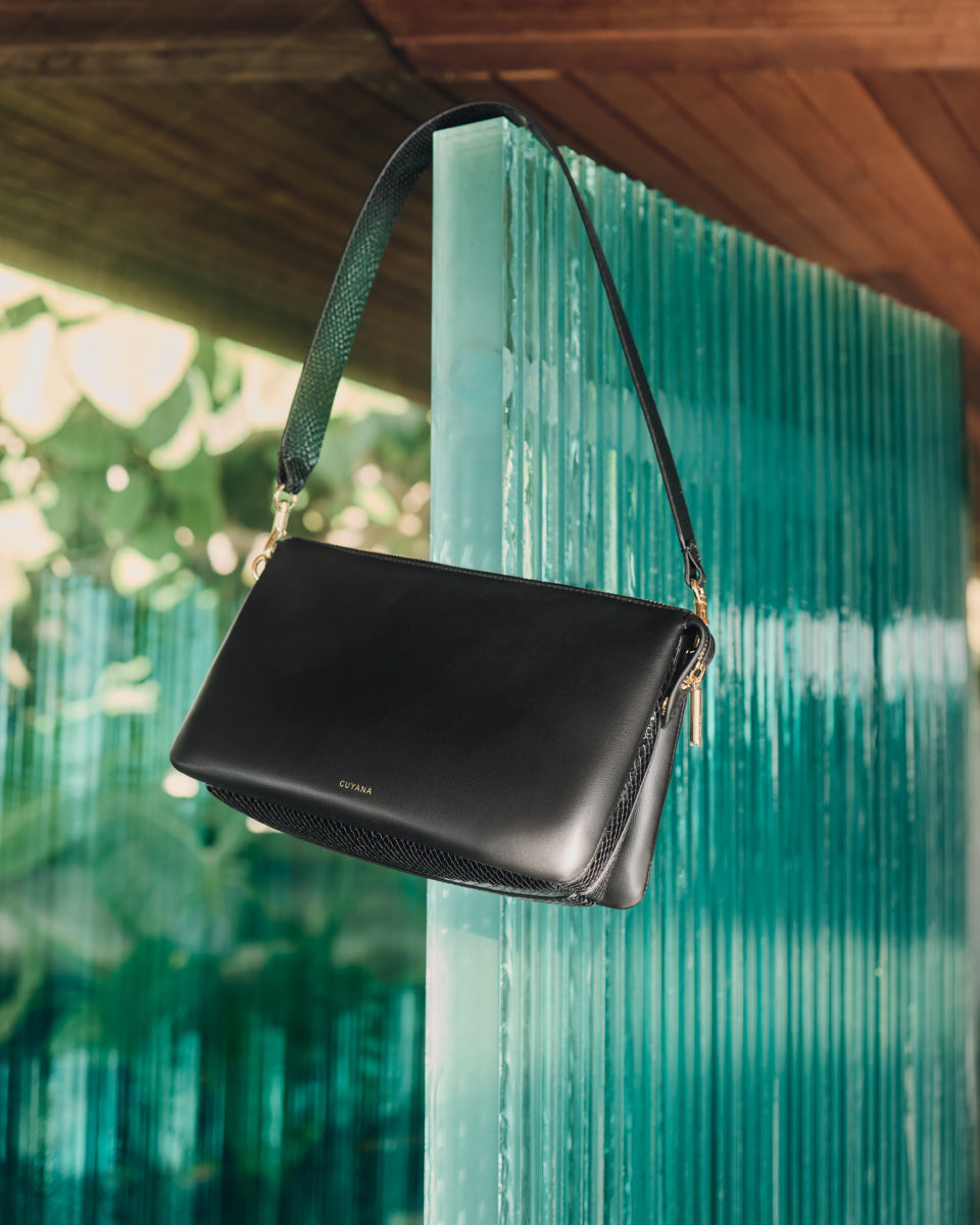 Handbag with strap hanging on glass wall.