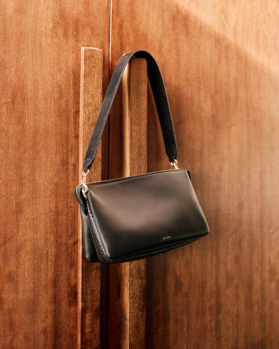 Handbag hanging on a wooden door handle.