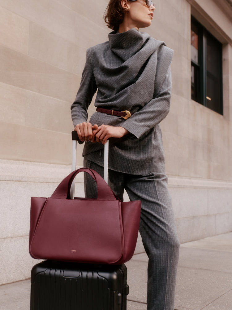 Person in a suit holding luggage with a travel bag on top of it