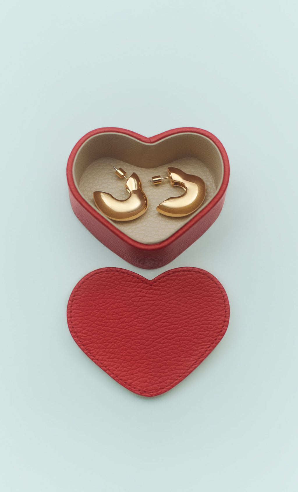 Heart-shaped box with jewelry inside and lid beside it.