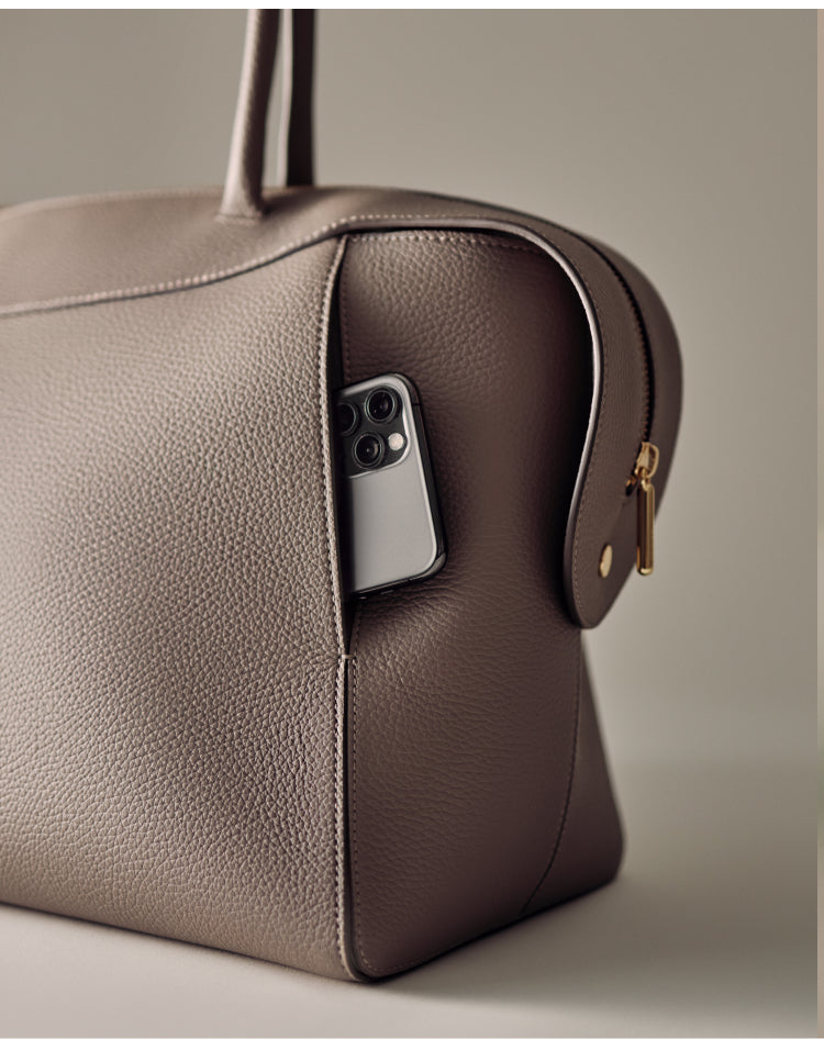 Travel bag with a phone in side pocket on light surface.