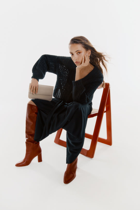 Woman sitting on a chair holding a clutch bag