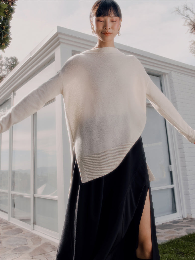 Woman standing in front of a house with arms outstretched.