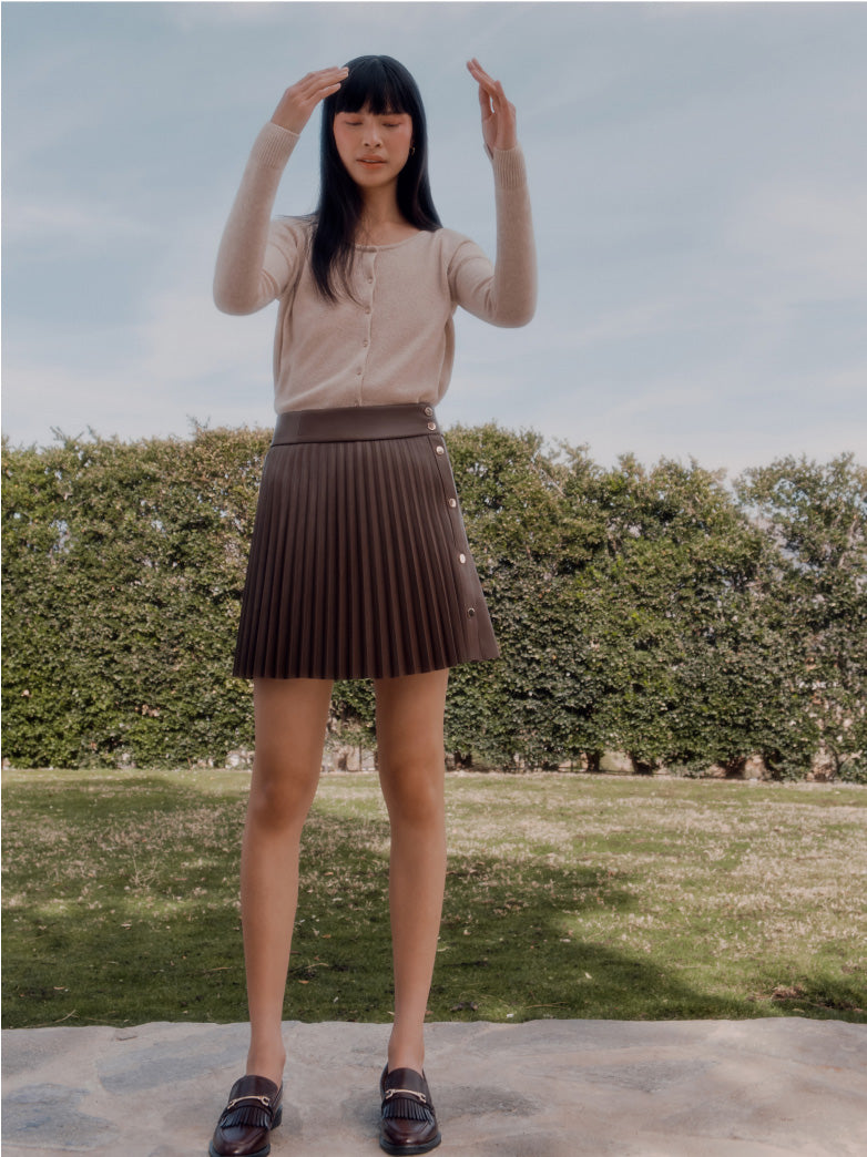 Woman standing outdoors with hands raised above her head