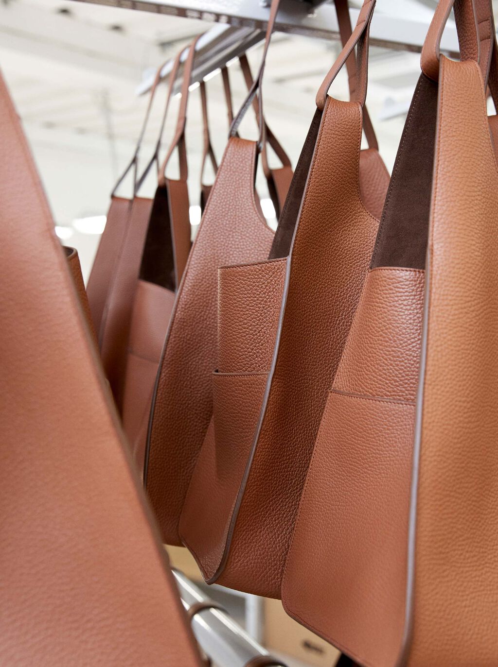 Several handbags hanging on a rack.