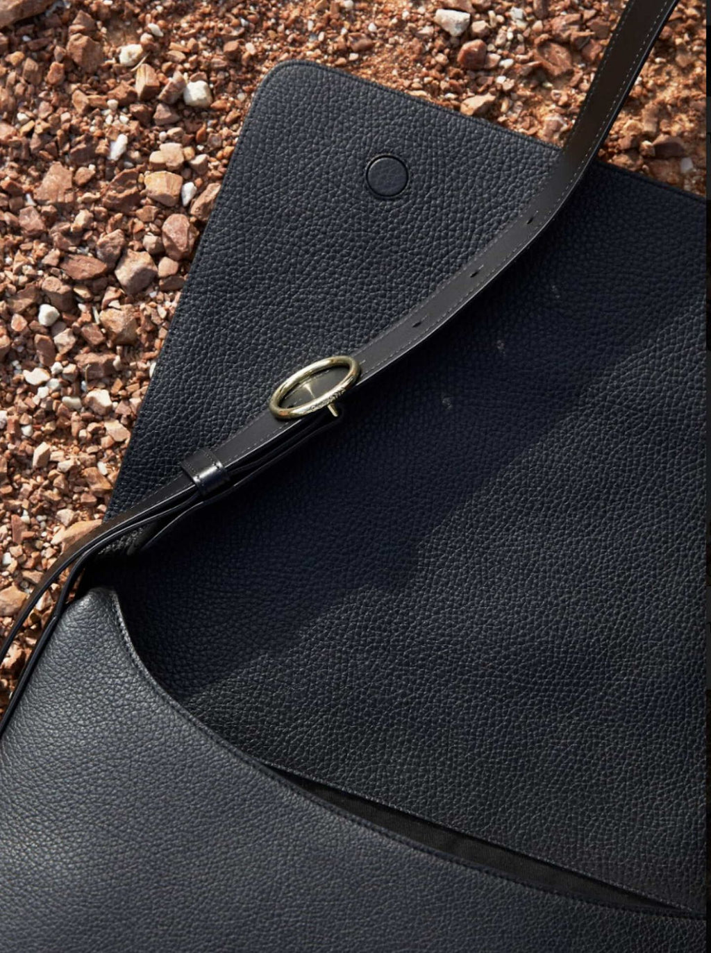 Close-up of a bag with a strap and metallic buckle on a textured surface.