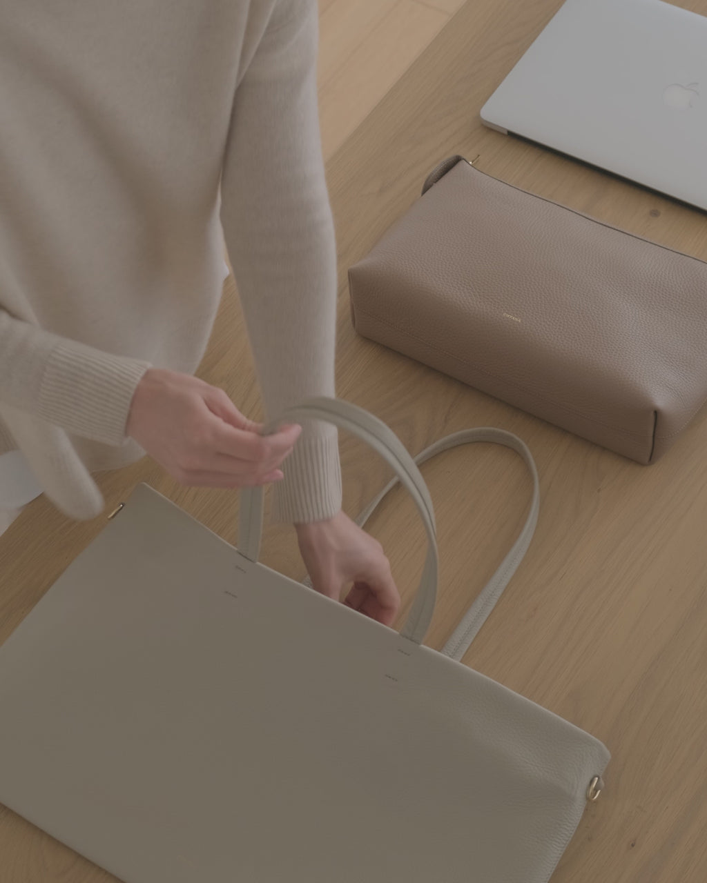 Person putting a laptop, zipper pouch, keychain into an Easy Zipper Tote