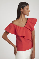 Woman in an off-shoulder top with layered ruffles, standing sideways.