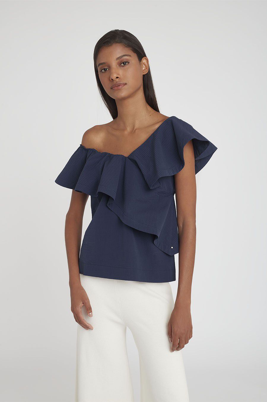 Woman standing in an off-shoulder top and contrasting pants.