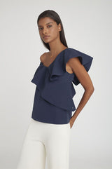 Woman in a ruffled sleeve top posing with her hand on her hip.