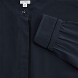 Close-up of a shirt with a buttoned placket and gathered sleeve detail