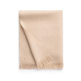 Folded blanket with fringe on a plain background.