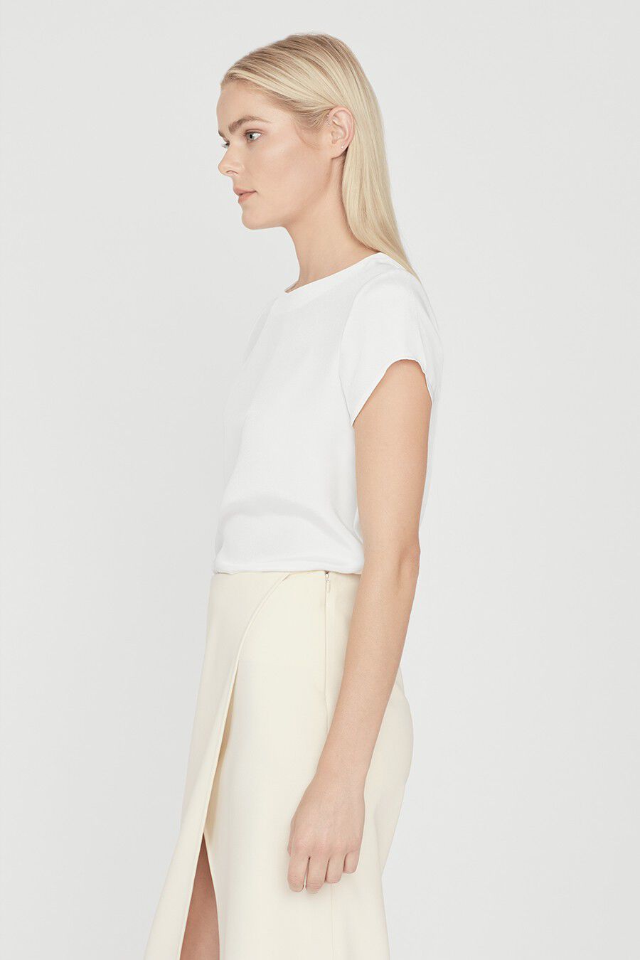Woman in profile wearing a short-sleeved top and skirt.