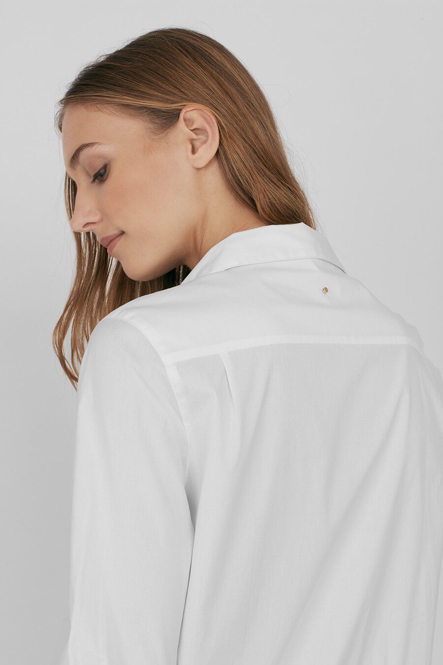 Woman looking down, wearing a button-up shirt, side profile view.