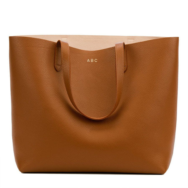 Leather tote bag with handles and personalized initials 'ABC'.