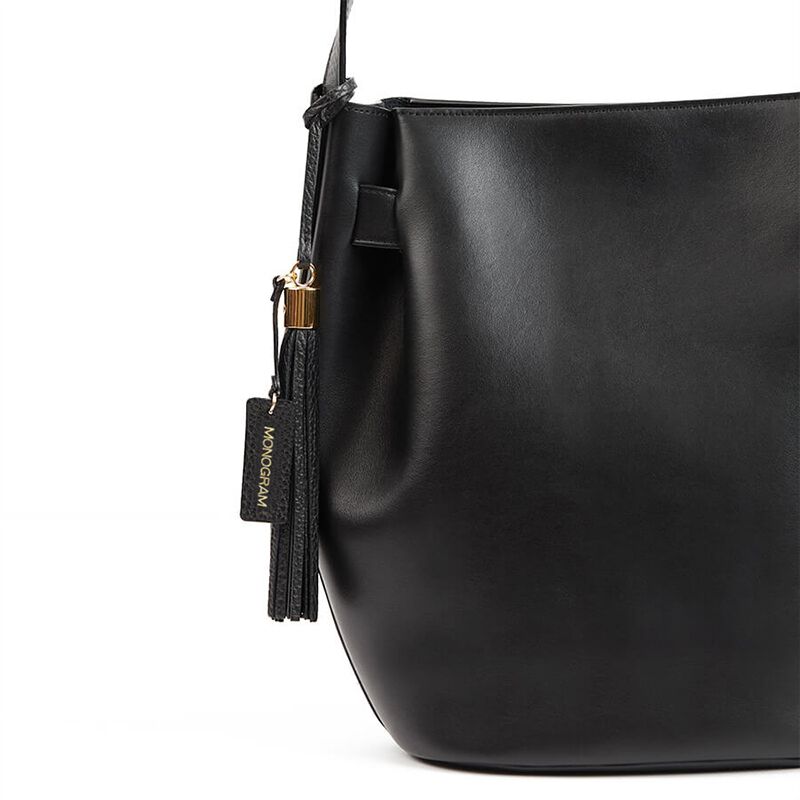 Side view of a handbag with a zipper and a branded tag.