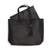 Handbag with handles and a tassel on white background.