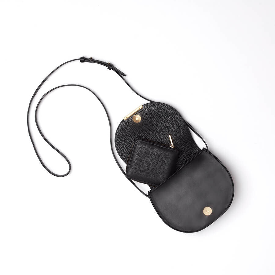 Two overlapping handbags with long straps on a plain background.