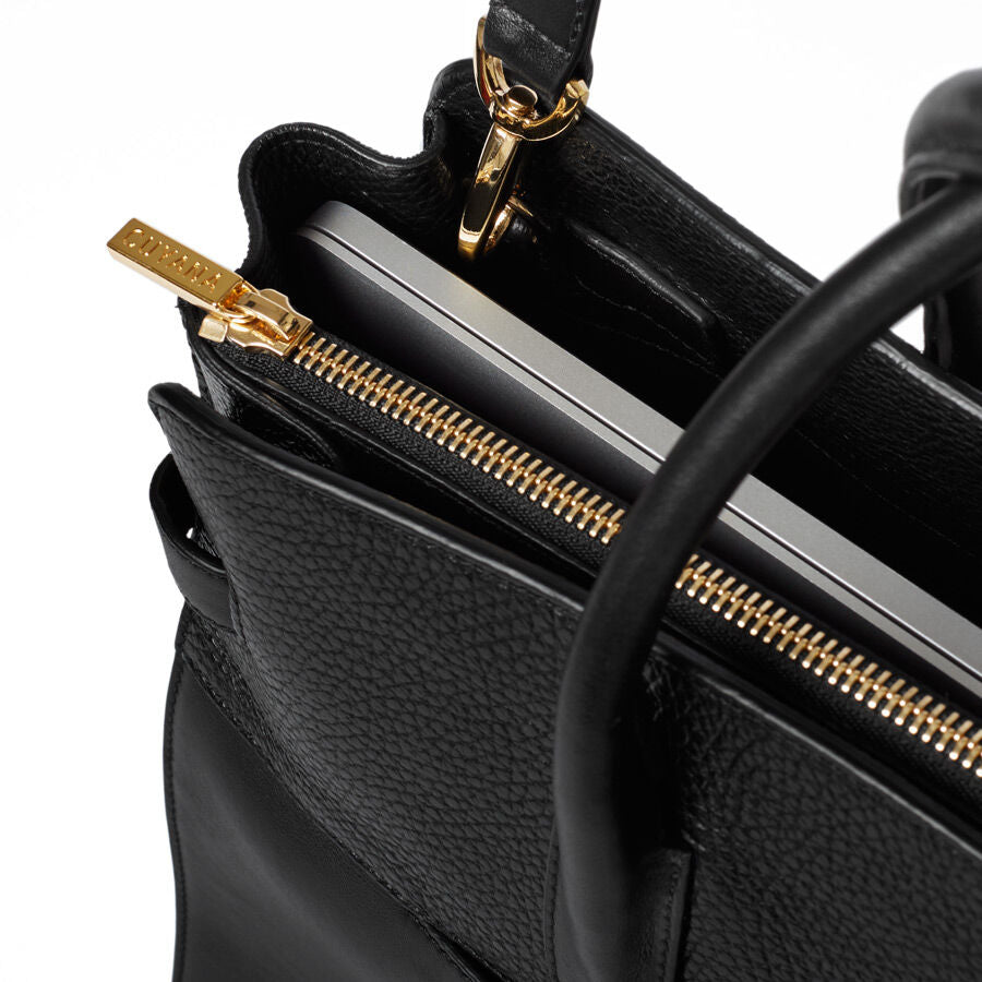 Close-up view of an open handbag with visible zipper and inner contents.