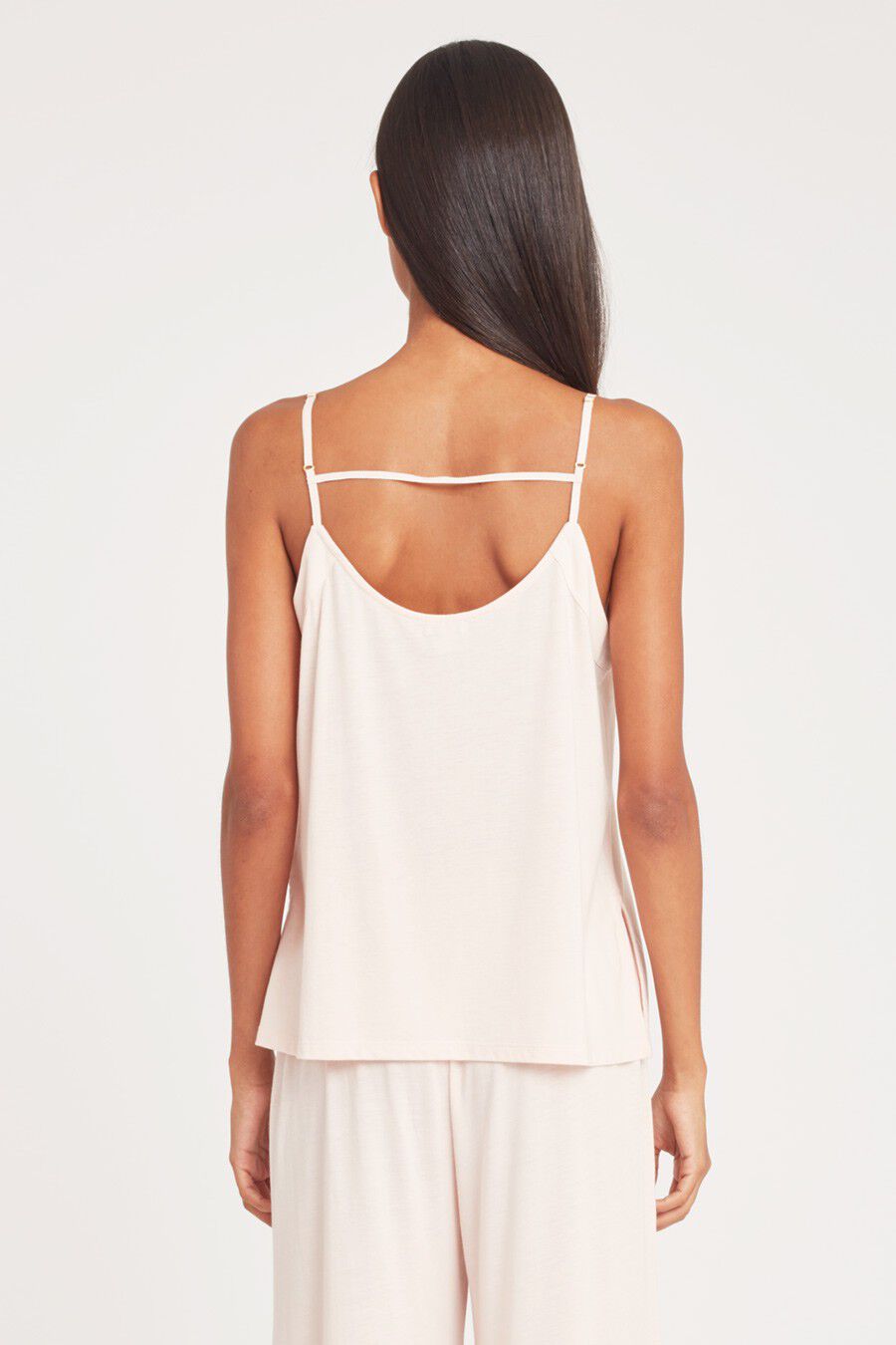 Woman seen from behind wearing a strappy top and pants.