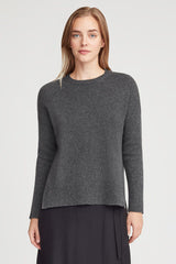 Woman in a sweater standing straight, looking at camera