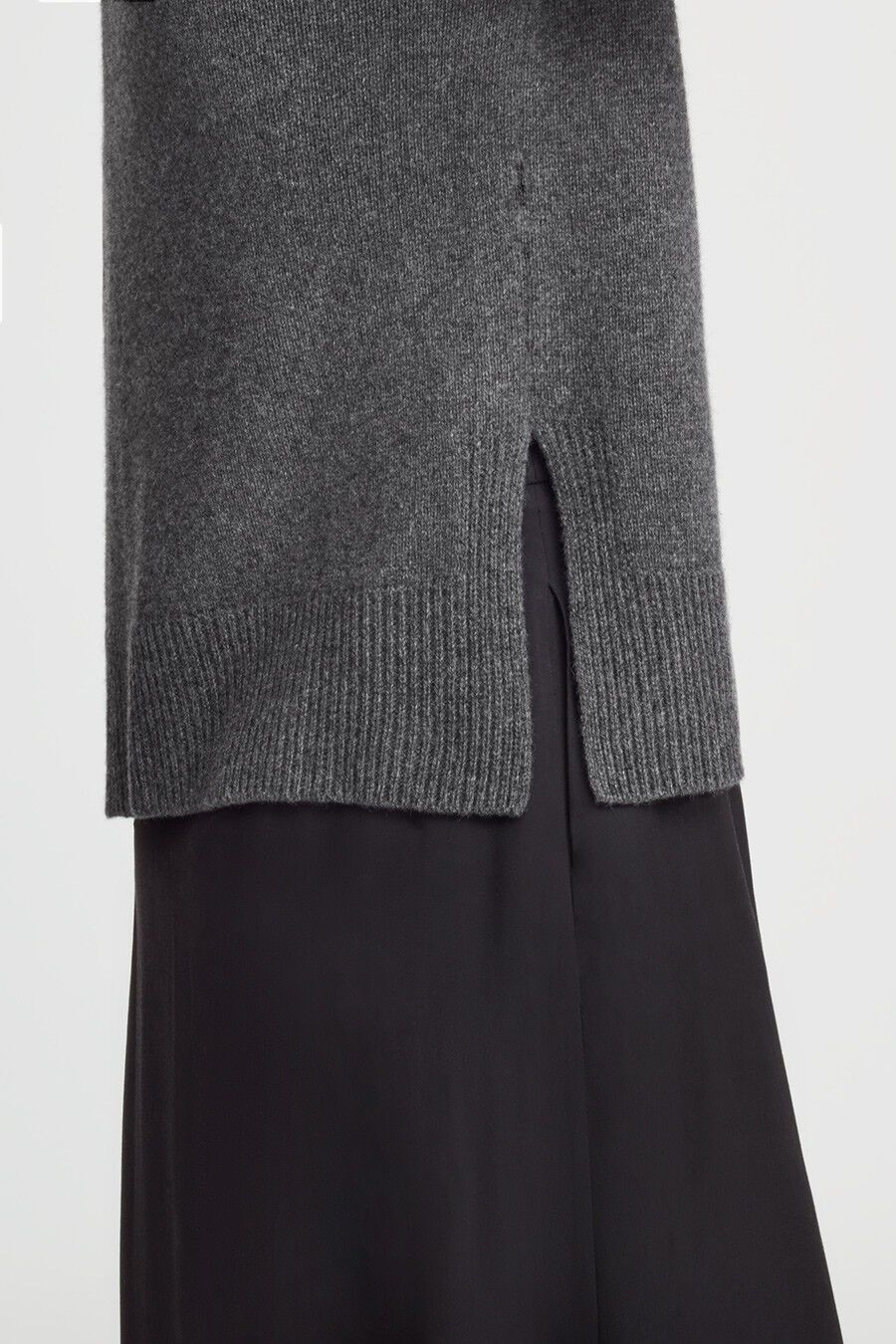 Close-up of a sweater over pants with a slit detail at the hem.