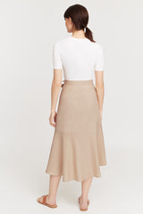 Woman in a skirt and top standing with her back facing the camera.