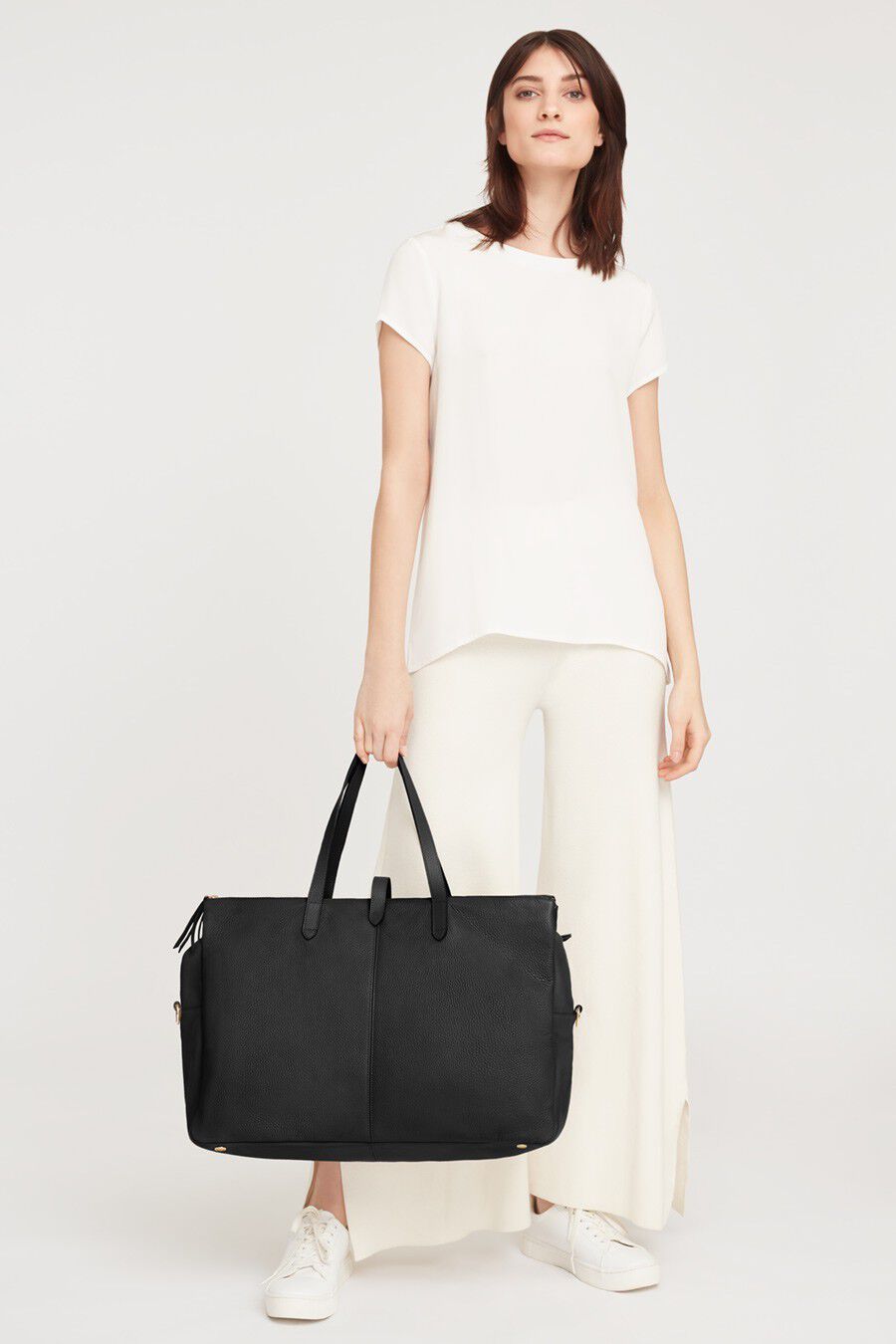 Woman standing and holding a large bag