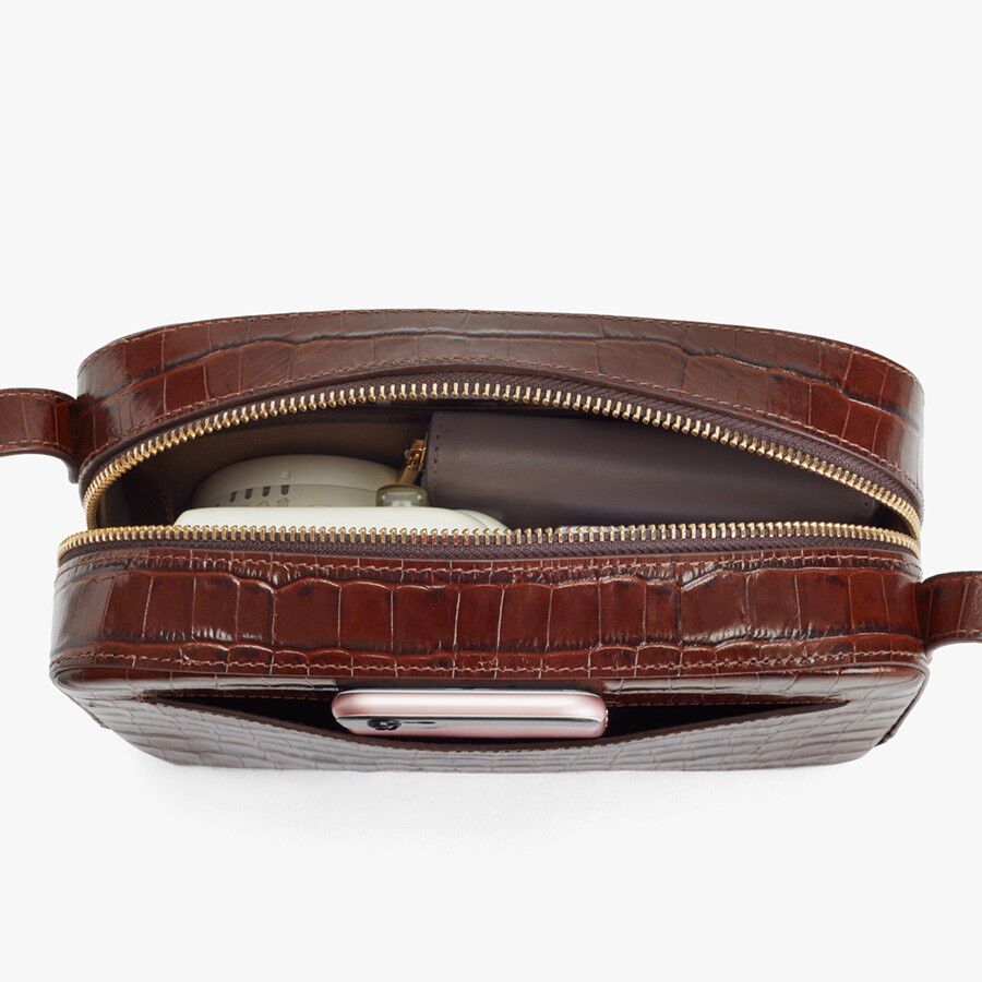 Belt bag with zipper open, showing a smartphone and notebook inside.