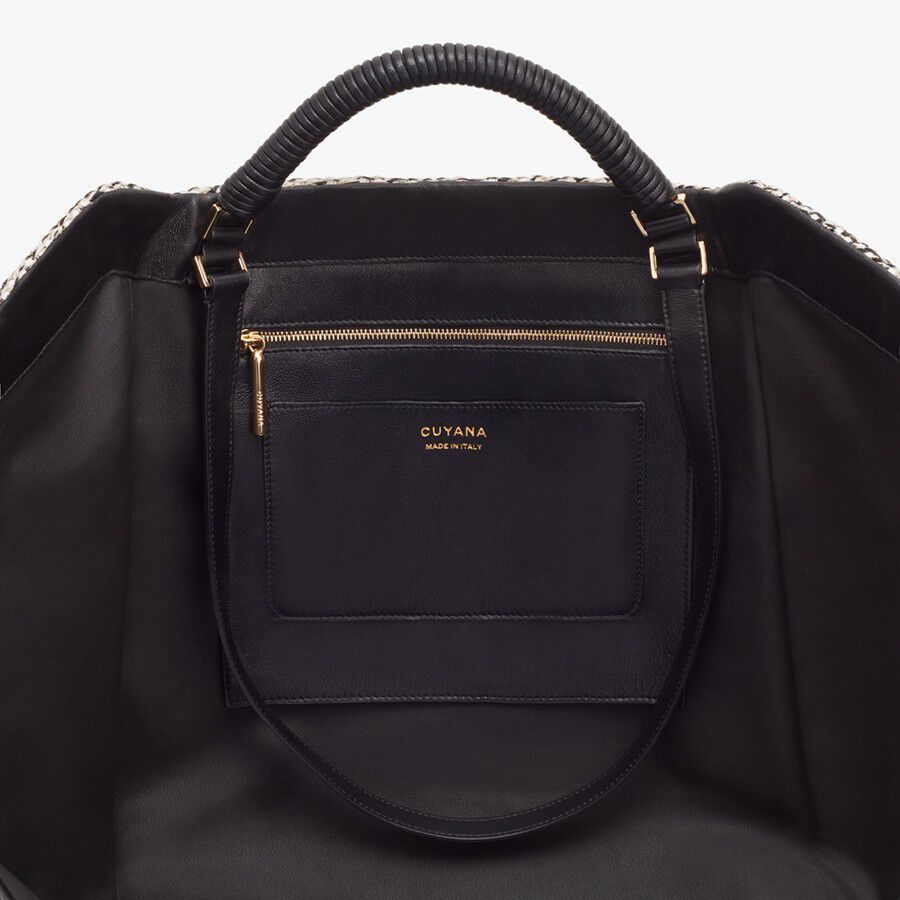 Close-up of a handbag with top handles and a front zipper pocket.