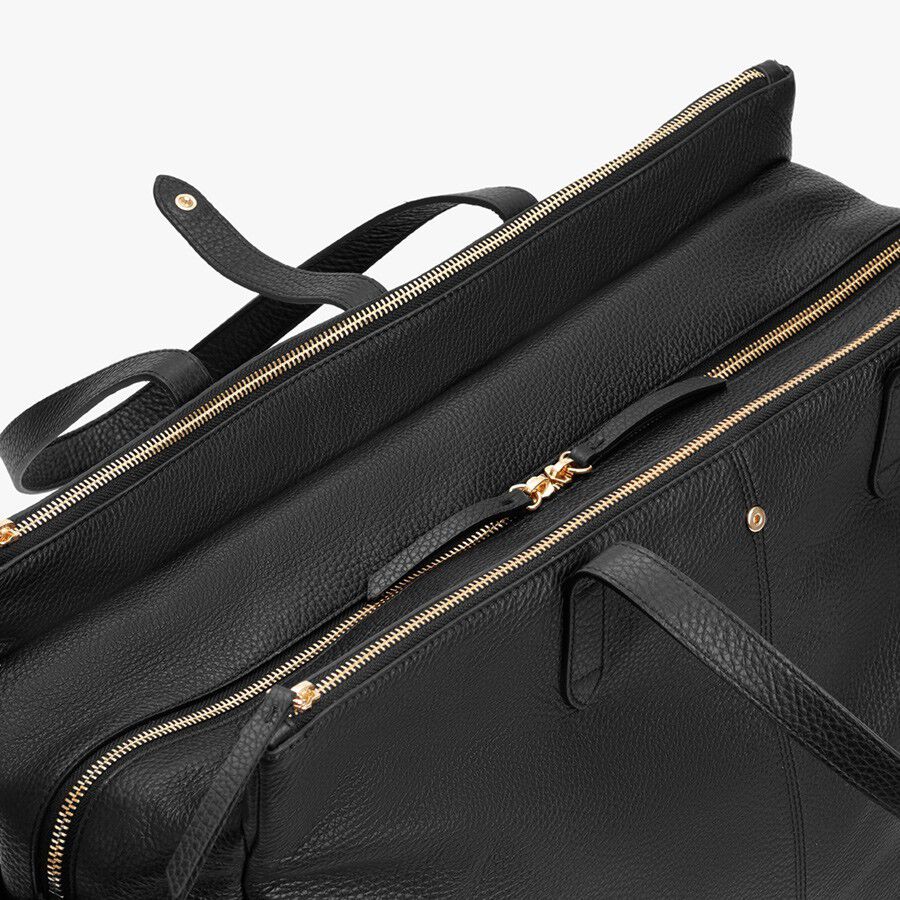Close-up view of a leather bag with multiple zippers and a handle.