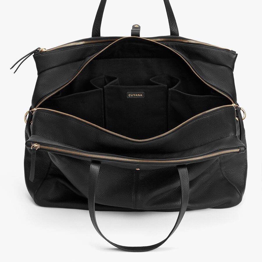 Open handbag with multiple compartments and zippers, standing upright.