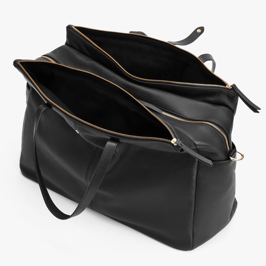 Open handbag with multiple compartments and zippers, viewed from above.
