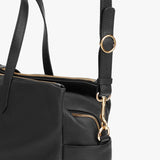 Close-up of a handbag with external pockets and an adjustable shoulder strap.