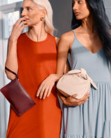 Two women holding handbags standing close together.