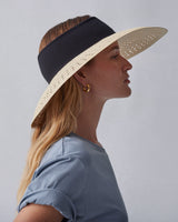 Woman in a profile view wearing a wide-brimmed hat and a blouse.