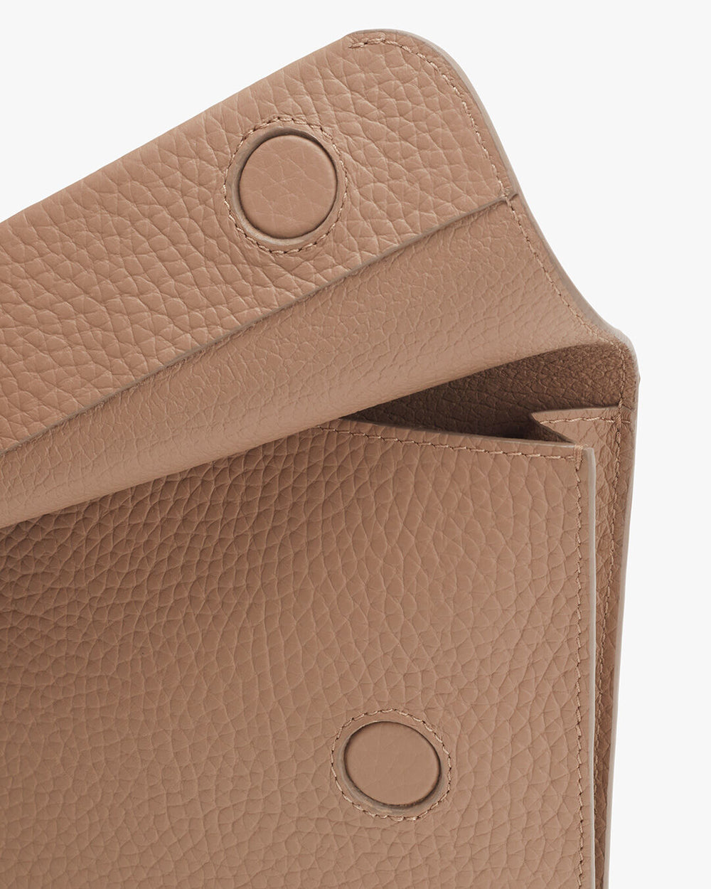 Close-up view of a textured handbag with flap closure and snap buttons.