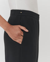Person standing with their hand in the pocket of their trousers.