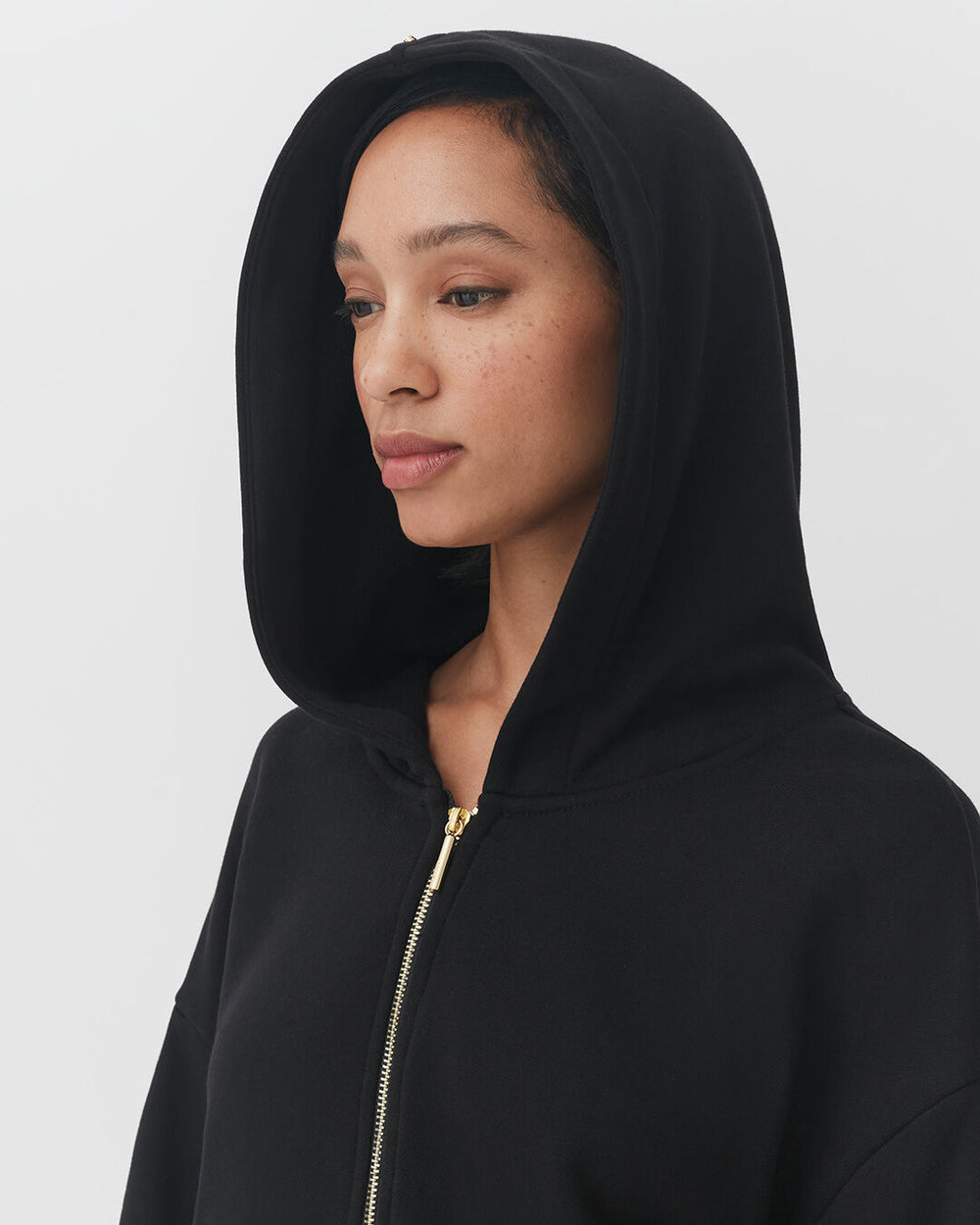Woman wearing a hooded jacket with a zipper.
