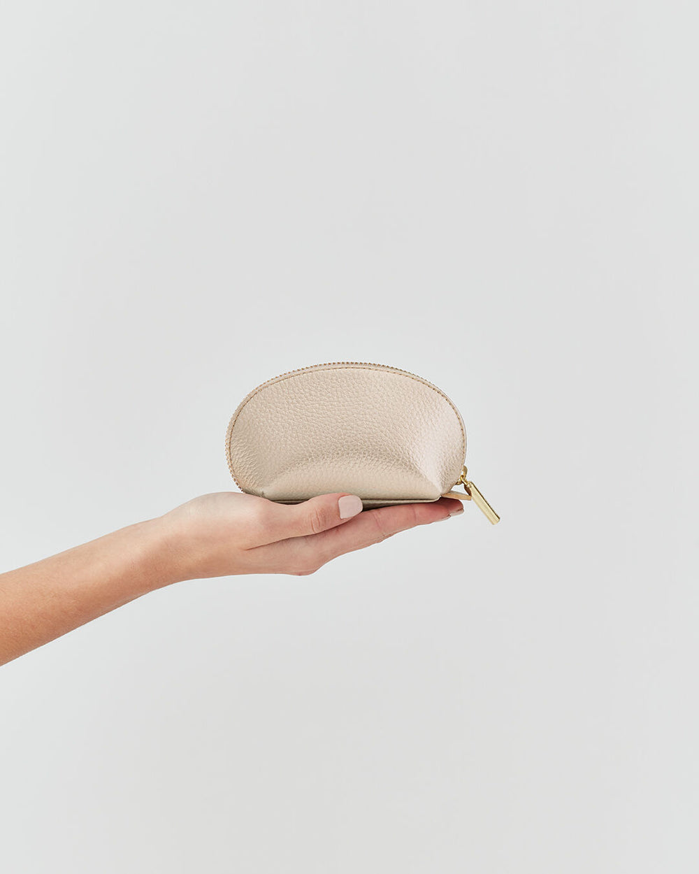 Hand holding a small zippered pouch against a plain background.