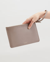 Hand holding a small clutch purse by the strap.