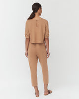 Woman standing, viewed from behind, wearing a casual outfit.