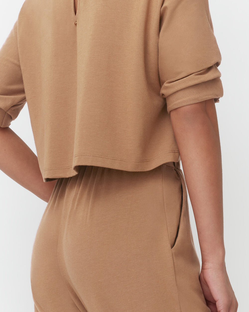 Person wearing a short-sleeved top and pants, partial view from side.
